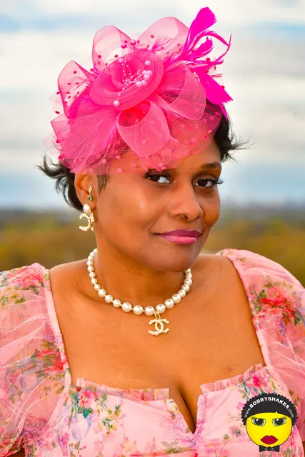Guest in a hot-pink fascinator and pearls