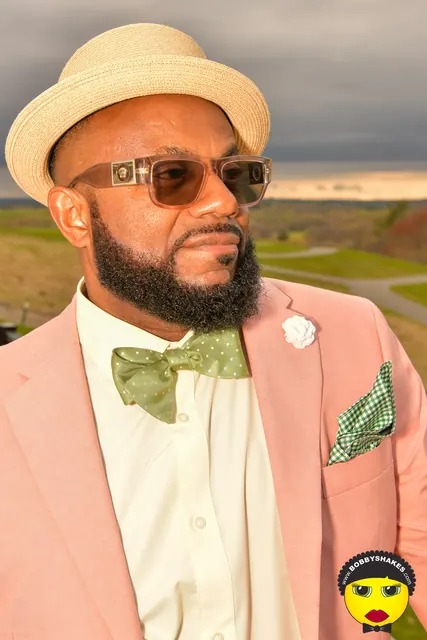 Guest in a pink blazer, green bow tie and straw hat