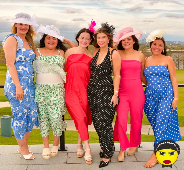 Six friends in colorful jumpsuits and hats on the terrace